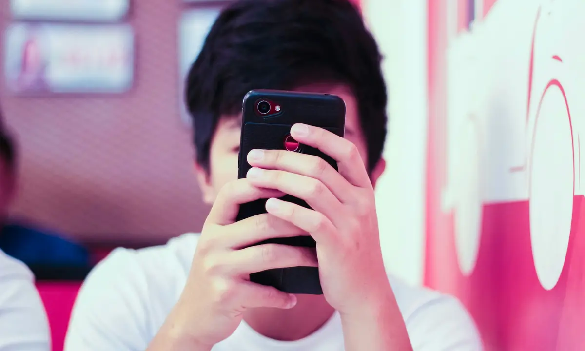Ragazzo che utilizza uno smartphone tenendolo davanti al viso