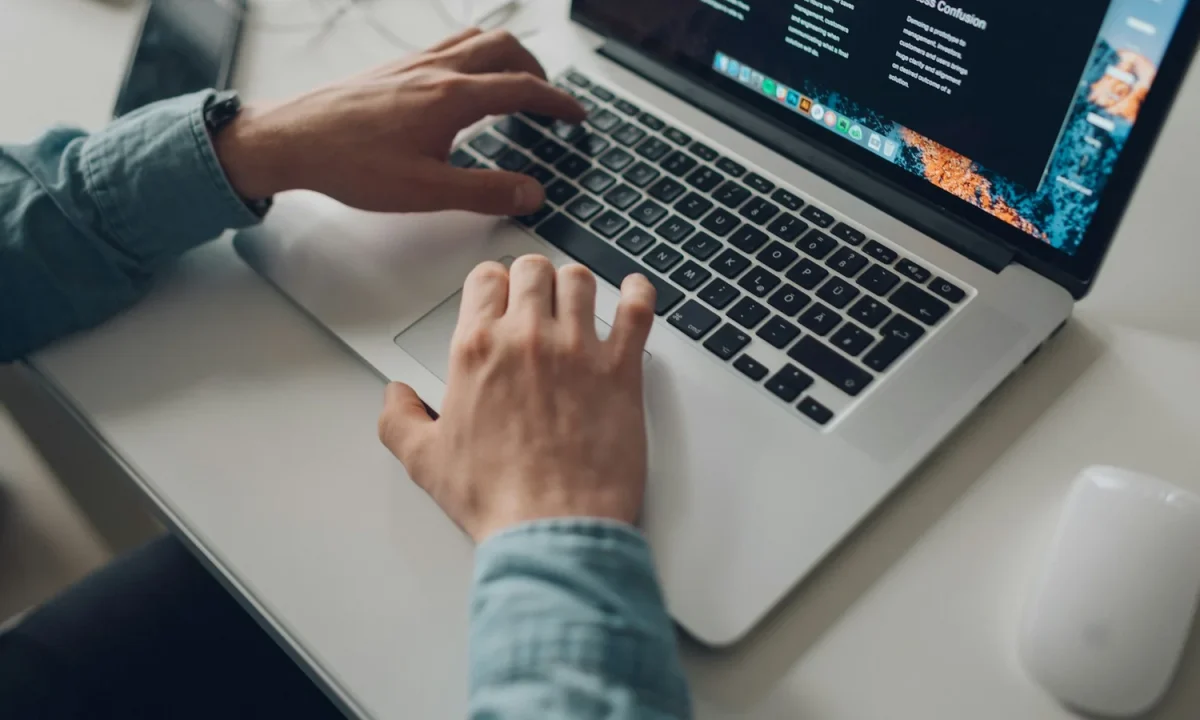 Mani di una persona che scrive sulla tastiera di un computer portatile.