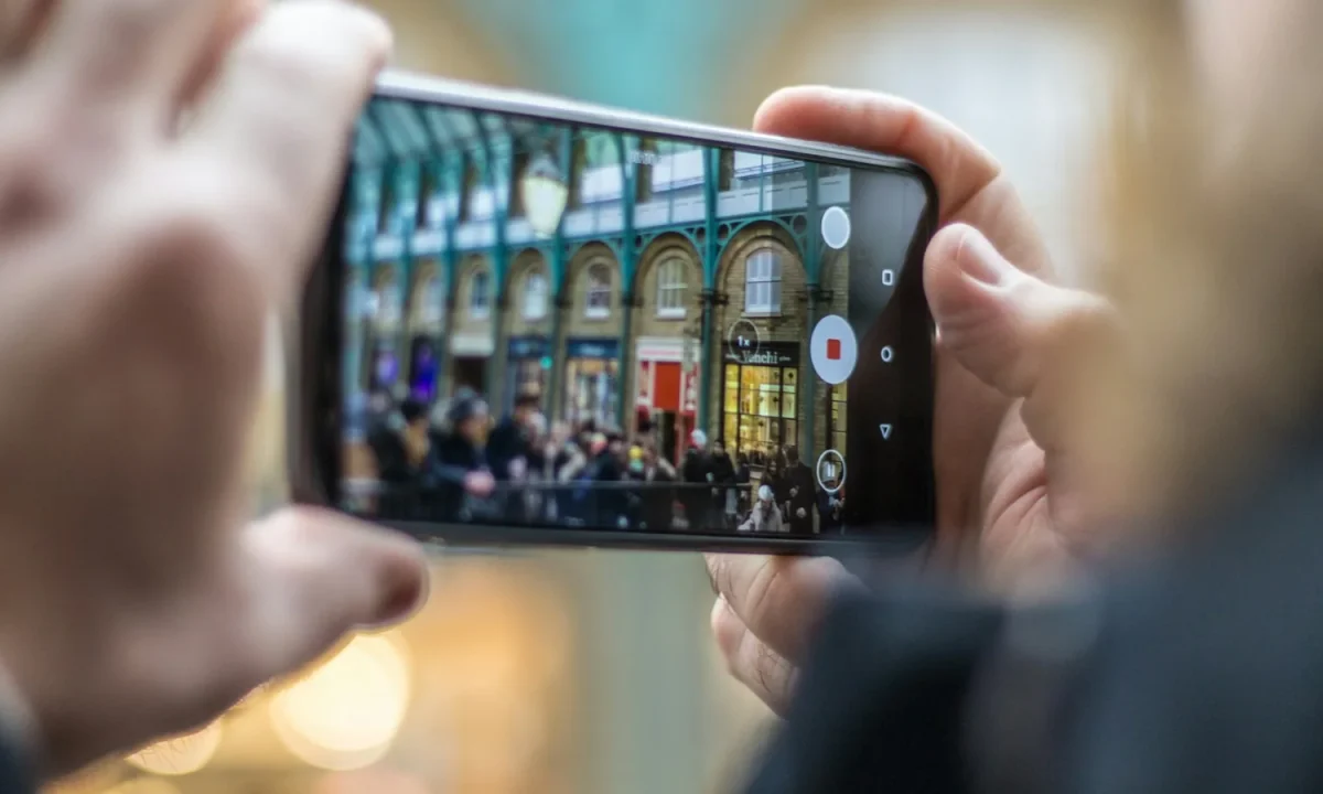 Una persona riprende una strada con lo smartphone tenuto in orizzontale.